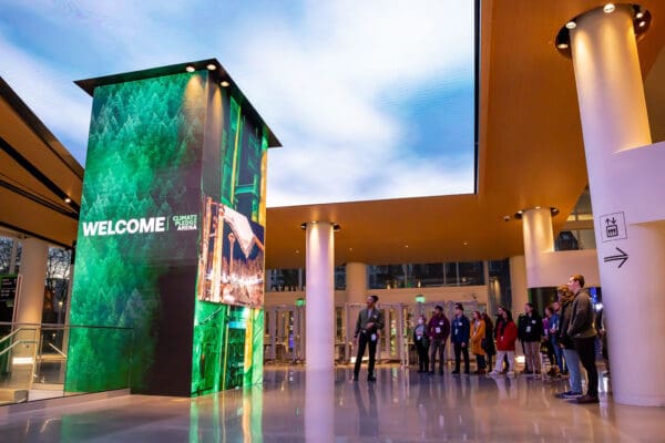 music experience project seattle Welcome sign at the Climate Pledge Arena with people in a group beneath it